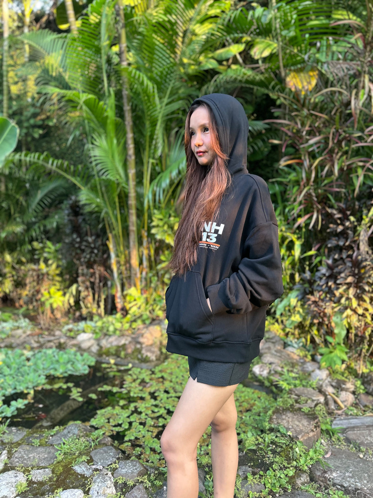NH13 black hoodie worn by model with hood up